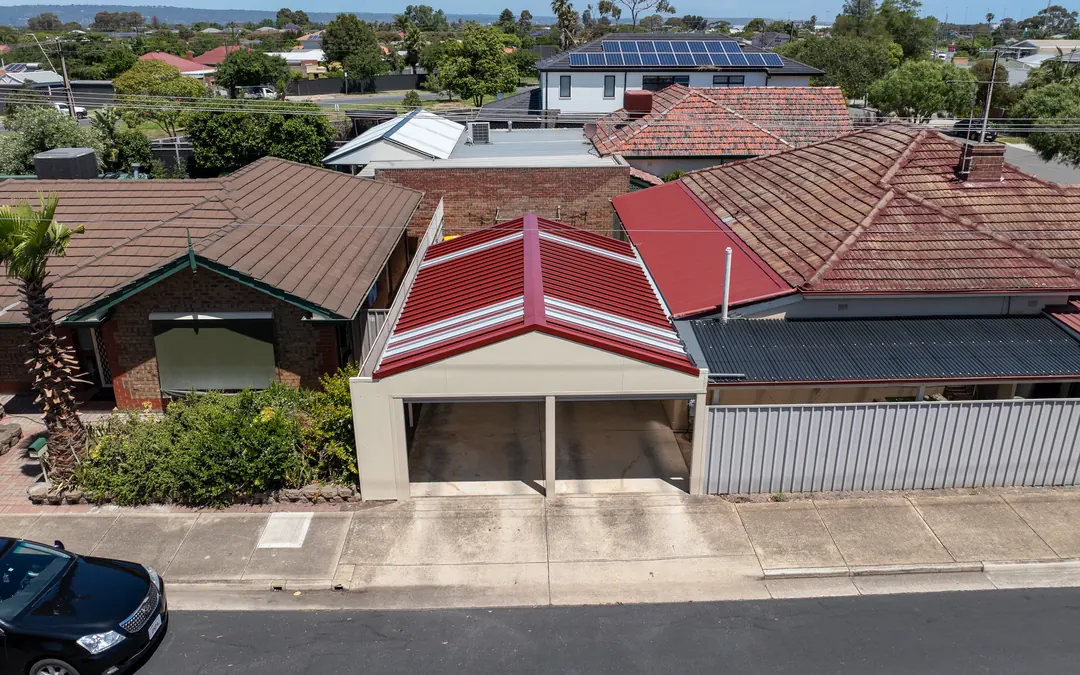 Drone view of a new red-roofed gable carport on a Brooklyn Park street