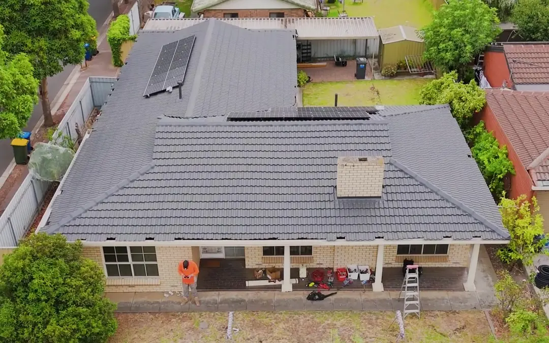 Drone view of a brick home during a gutter replacement, new lengths laid out on the lawn