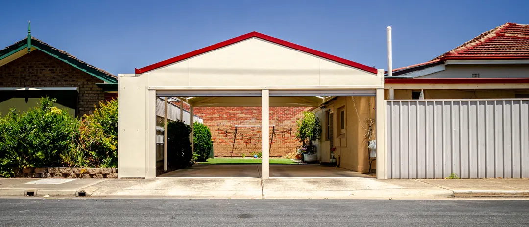 A new gable carport with red trim over the driveway of a Brooklyn Park home