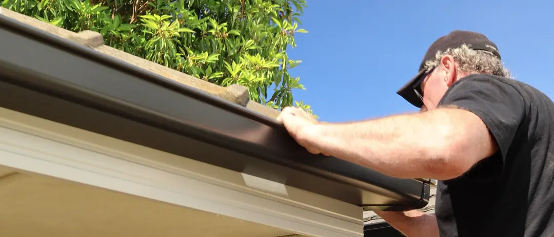 A new Colorbond gutter being pressed onto its brackets