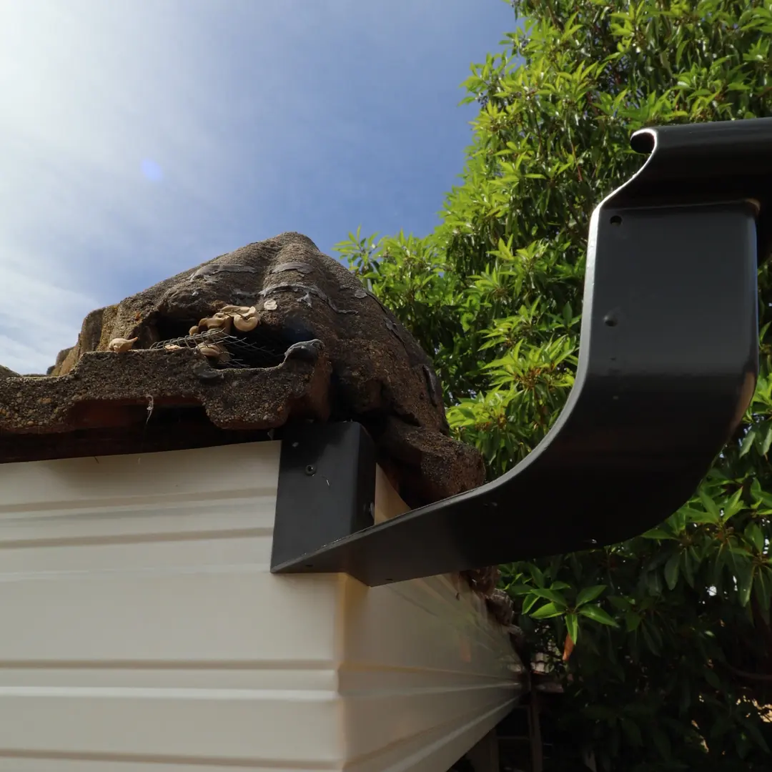 A new gutter bracket fixed to fresh fascia under the roof tiles