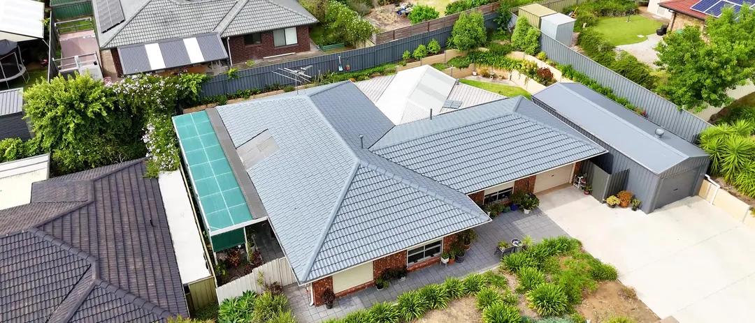 Drone view of a freshly restored tile roof next to a neighbour's untreated one