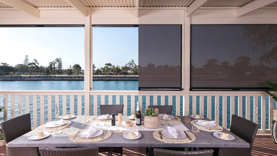 Ziptrak® outdoor blinds half down on a waterfront alfresco area (product photo: Ziptrak)